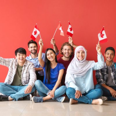 Group,Of,Students,With,Canadian,Flags,Sitting,Near,Color,Wall